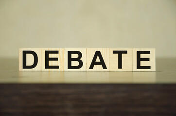  the word debate is written on wooden cubes that lie on a black table