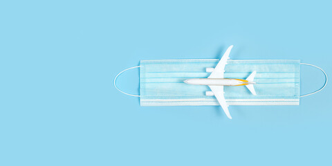 Plane model and face mask on a blue background. Flight impact of coronavirus (COVID-19) concept.
