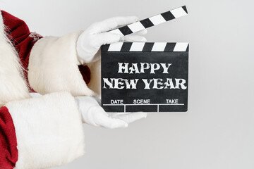 Santa Claus is holding a cracker in his hands - a numerator with the text - HAPPY NEW YEAR