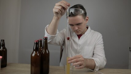 young master technologist brews beer at home, pours beer into bottles, checks the sugar level in beer, checks the percentage of alcohol in beer, checks the quality of the brewed