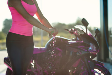 Plakat Close up woman's hands squeeze moisture out of the rag while wipes sport motorcycle at self service car wash.