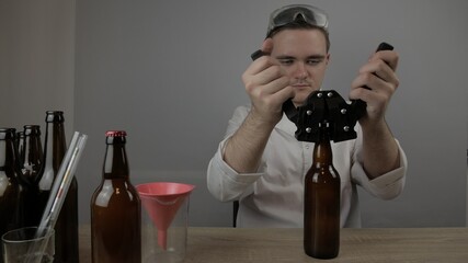 young master technologist brews beer at home, pours beer into bottles, checks the sugar level in beer, checks the percentage of alcohol in beer, checks the quality of the brewed
