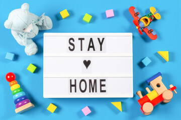Stay at home. Lightbox with text STAY HOME and baby kid toys on blue background. Coronavirus, Covid-19, quarantine and social distancing concept