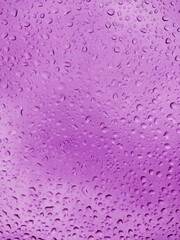 Abstract background with purple drops on the glass window.