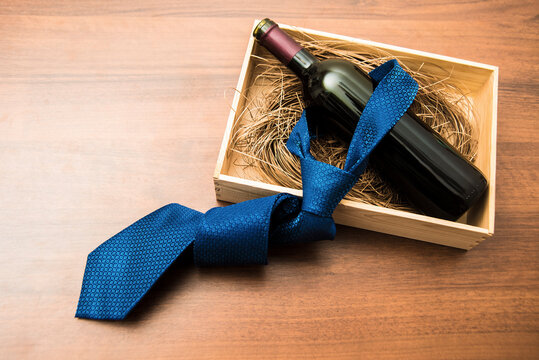 one bottle of red wine with blue tie in wooden box on wood table background. empty copy space for object or inscription. Father's day holiday idea, sign, symbol, concept.