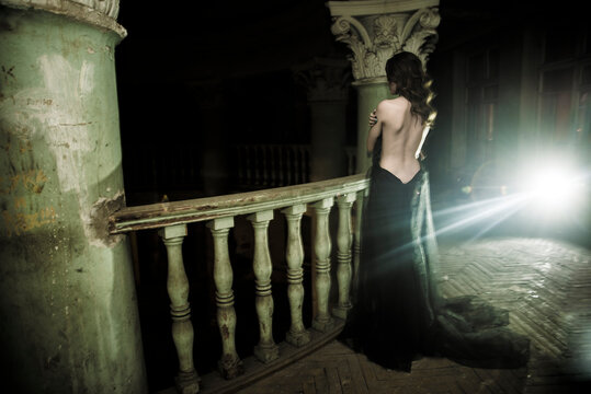 Beautiful young woman with naked back, retro black dress. rear view. black widow or sexy bride. retro, vintage, historical interior.