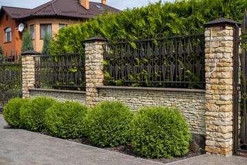 Iron wrought-iron fence between decorative brick columns in front of a residential building.