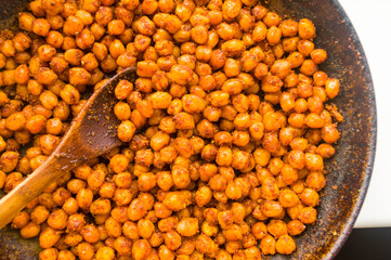 Cooking chickpeas with spices in a pan, close-up