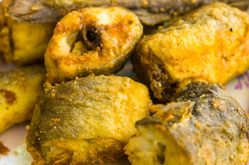 Pieces of navaga fish in batter, fried in oil in a pan.