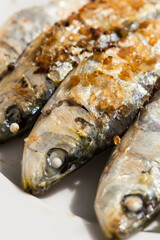 Sardines cooked over charcoal fireVertical Macro Up View Of Four Cooked, Seasoned Sardines In A Row, In Traditional Malagenean Cuisine Dish Espeto de Sardinas, Selective Focus