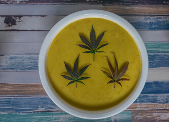 Marijuana butter with violet and green leafs in white plastic basin