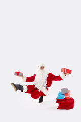 Joyful Athletic Santa Claus jumps high and dances with happiness with gifts on a white background. Concept for Christmas and New Year holidays and sales.