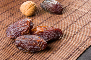 Big luxury dried date fruit on the bamboo mat, kurma ramadan kareem concept, close up.