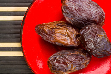Big luxury dried date fruit in bowls on the bamboo mat, kurma ramadan kareem concept, close up.