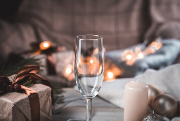 Champagne glass on a Christmas background in a cozy home atmosphere in the evening, with glowing lanterns in the background. The concept of New year and Christmas.