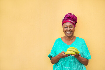 African woman smiling on camera holding a bunch of bananas