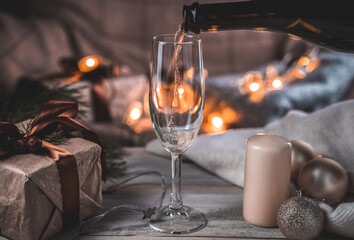 Pouring champagne into a glass on a Christmas background. Holiday background. The concept of New year and Christmas.