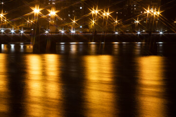 Night city view of the old bridge across the river lanterns six-pointed stars with smooth water reflections