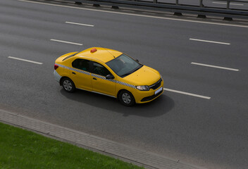 Fototapeta na wymiar Yellow Taxi Drives on the City Street