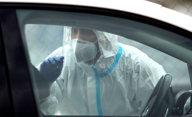 Medical staff member with mask and protective equipment performs Coronavirus nasal swabs test tubes...