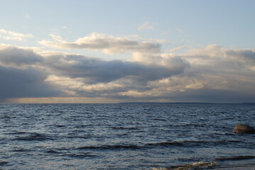 Clouds in the blue sky. The Gulf of Finland. Waves. Stone in the water.