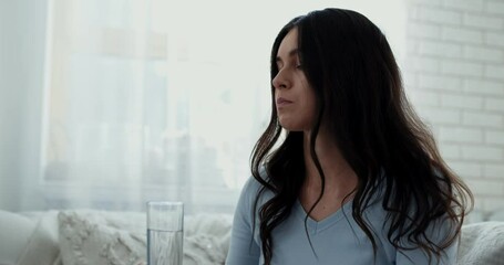 Depression treatment concept. Upset woman taking antidepressant drug or tranquilizer at home