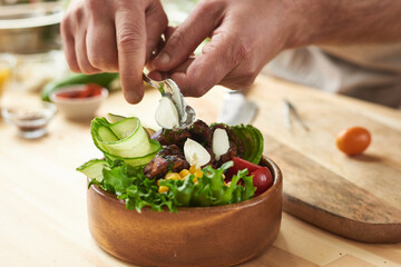 Close-up of elegant wooden bowl with fresh vegetables and meat prepared by chef