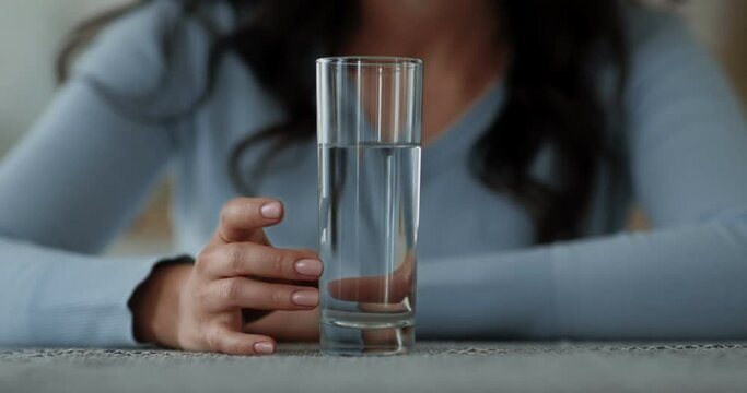 Nervous woman knocking on glass with water, waiting for action of pills, close up