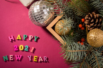 Fototapeta na wymiar Happy New Year greeting words made of wooden letters, gift boxes on a purple background decorated with festive tree branches.