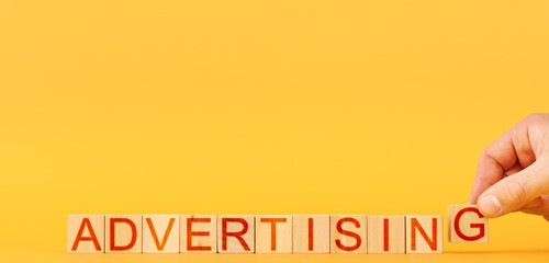 advertising. a man builds wooden blocks with the inscription advertising on an orange background