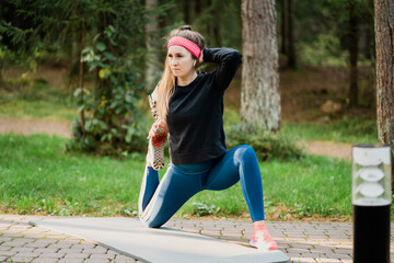 aerobics fitness sport female athlete trainer doing exercises posing for the camera. training in the Park among the trees clean air. tight, comfortable clothing for sports.