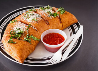 Italian Stromboli with sauce in a white and black plate