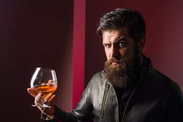 Whiskey. Brandy. Strong alcohol. Brutal man tastes whiskey. Degustation and tasting. Man in leather jacket drinks whiskey. Sommelier degustates whiskey.