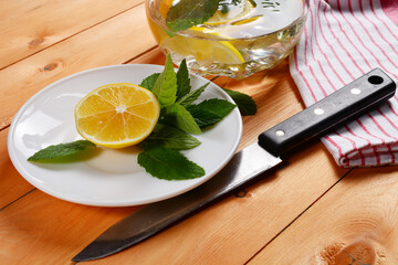 preparation of lemonade, a decanter of water with mint and lemon slices, lemon and fresh mint on a...