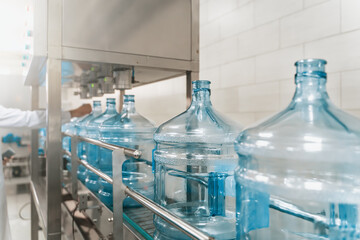 Water bottling conveyor line with plastic bottles or gallons on water factory production.