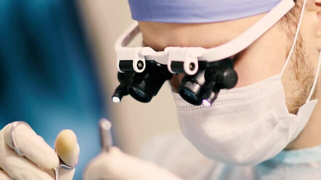 neurosurgeon operates in the operating room using glasses with microscopic lenses.