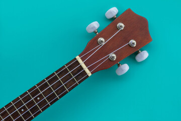 Closeup top view shot of a wooden ukulele with space for text on a blue background