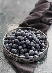 Closeup view of a cooling rack full of delicious and wet blueberries on a a dark and very wet wooden table as background.