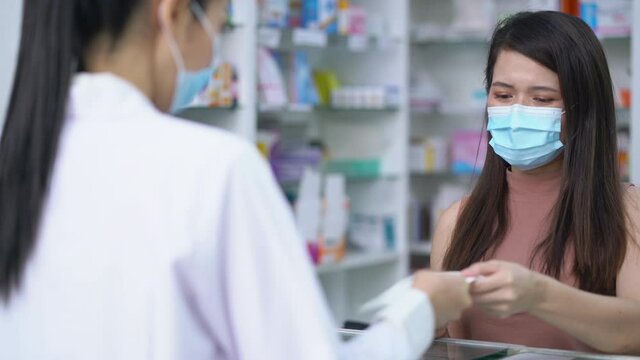 Woman Patient Customer Wearing Protective Hygienic Mask Giving Prescriptions Of Medicine To Pharmacist Woman In Pharmacy