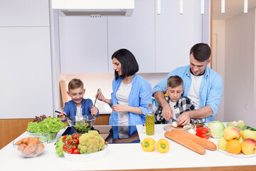 Happy caucasian family with two sons preparing healthy vegetarian breakfast with and vegetables on cozy kitchen.