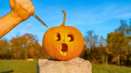 CLOS E UP: Halloween pumpkin with a shocked face is about to get stabbed