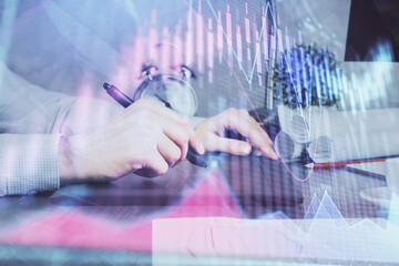 Double exposure of man's hands holding and using a phone and financial graph drawing. Analysis concept.