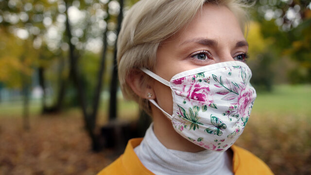 Portrait shot of young blond woman with fabric face mask in nature. High quality photo