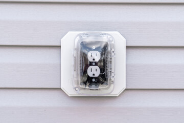Closeup view of black socket white double outlet with plastic cover on a house