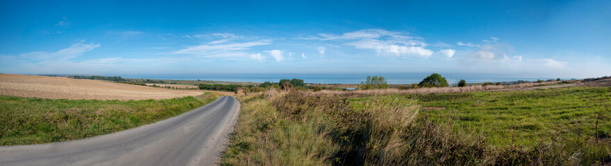 An empty road leads through a meadow towards Gold Beach, one of the five D-Day Landing Beaches,...