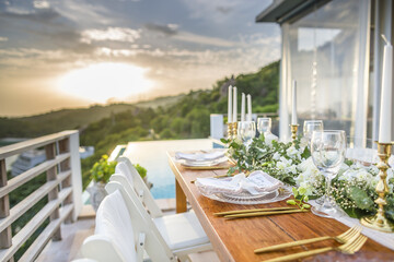 Fototapeta na wymiar Romantic Wedding Table Top Layout Table Spread no people tropical location with gold cutlery and scenic view of sunset with copy space
