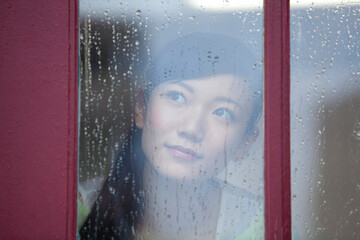 窓越しに外を眺める女性