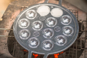 blurred abstract background of making desserts through a stainless steel stove with holes (Kanom Krok)is a traditional dessert made with coconut milk and sugar and then heated until the food is cooked