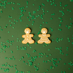 Happy New Year's set of cookies, gingerbread man in face mask from ginger biscuits glazed sugar icing decoration on green background, minimal seasonal pandemic winter holiday banner, invitation, flyer
