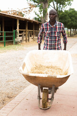 Young man farmer with barrow during working at farm outdoor